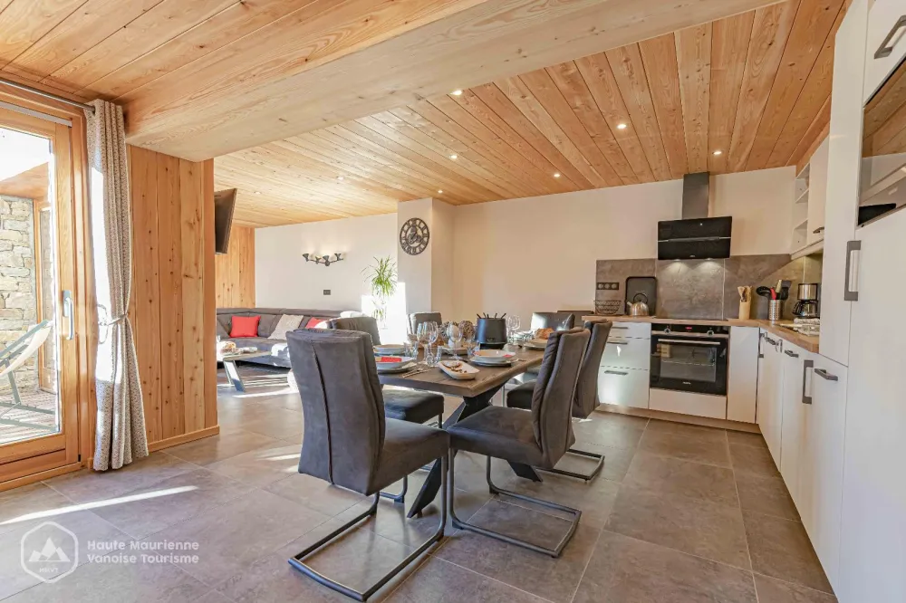 La grande pièce de vie de l'appartement Feiche, avec une cuisine ultra équipée ouverte sur l'espace repas, un salon plein Sud et deux larges baiens vitrées donnant sur la terrasse privative.