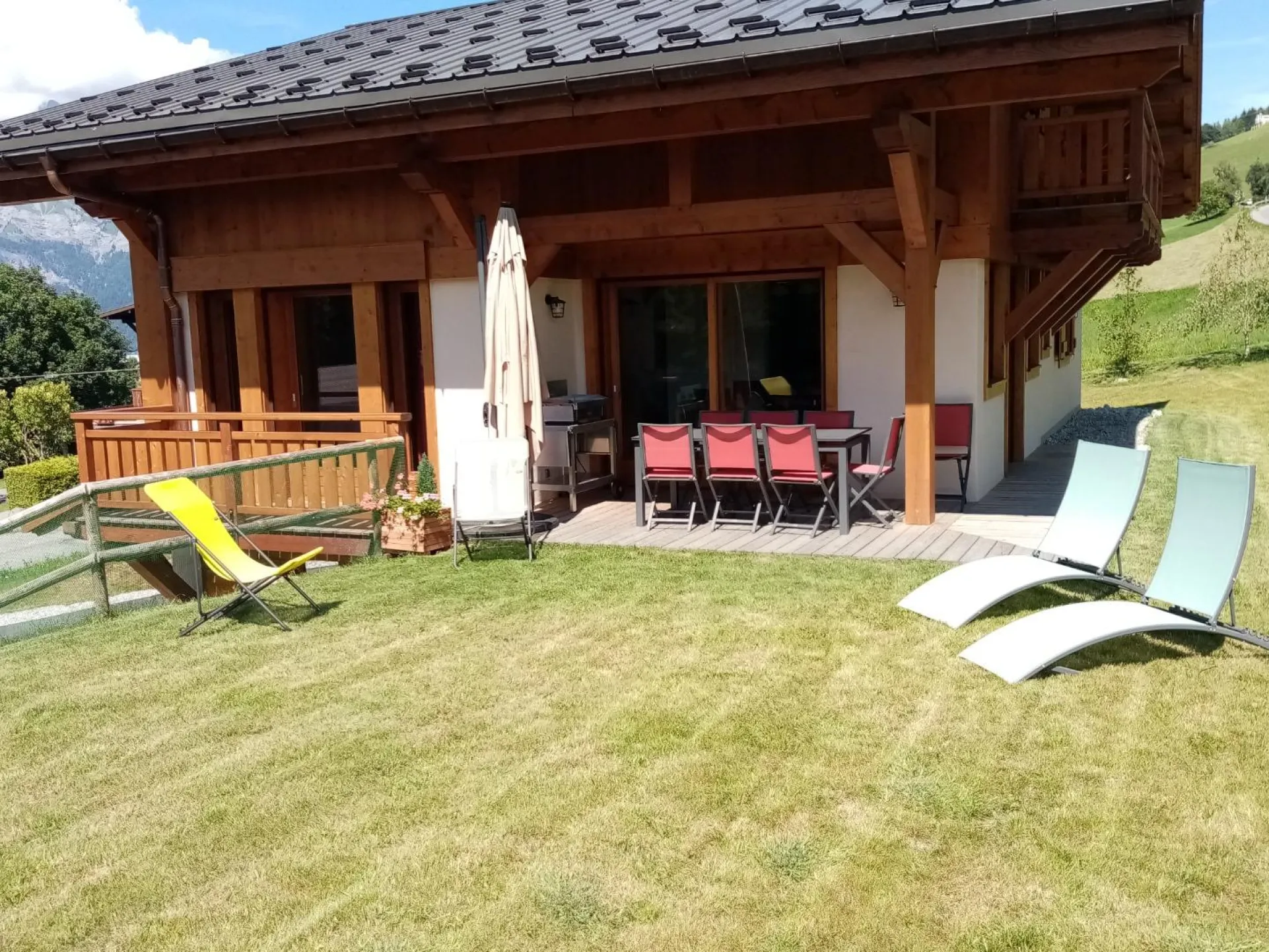 Terrasse extérieure aménagée accessible depuis la pièce principale avec coin repas ombragé et plancha électrique.