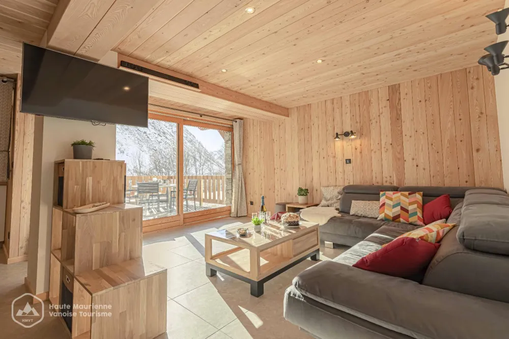 Le vaste salon de l'appartement, plein Sud pour se ressourcer face aux montagnes mais aussi parfaitement équipé pour se détendre avec TV connectée et barre de son bluetooth.