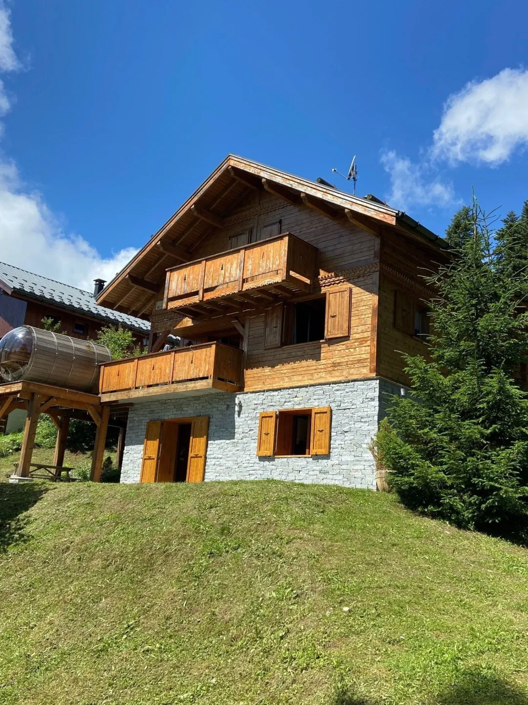 Le chalet en été avec sa terrasse privative, table et barbecue.