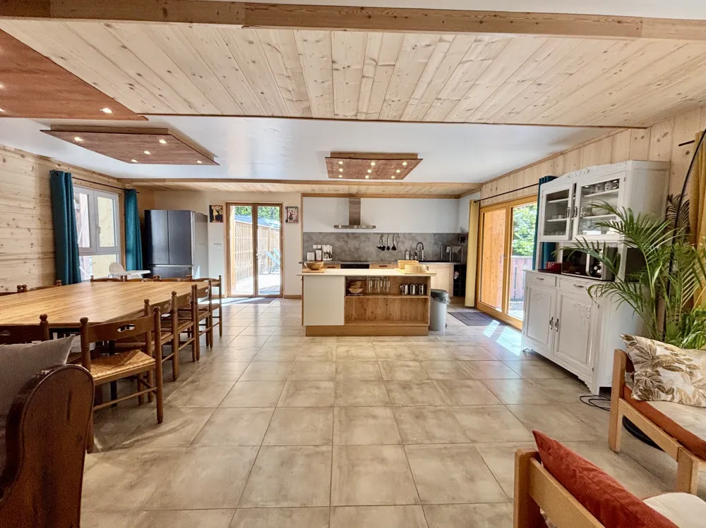 Une cuisine familiale pensée pour le plaisir d’être ensemble : matériaux chaleureux, éclairage doux et grande table au centre de la pièce. Les chaises confortables, dotées d’assises moelleuses, invitent à la détente et à de longues conversations après le 