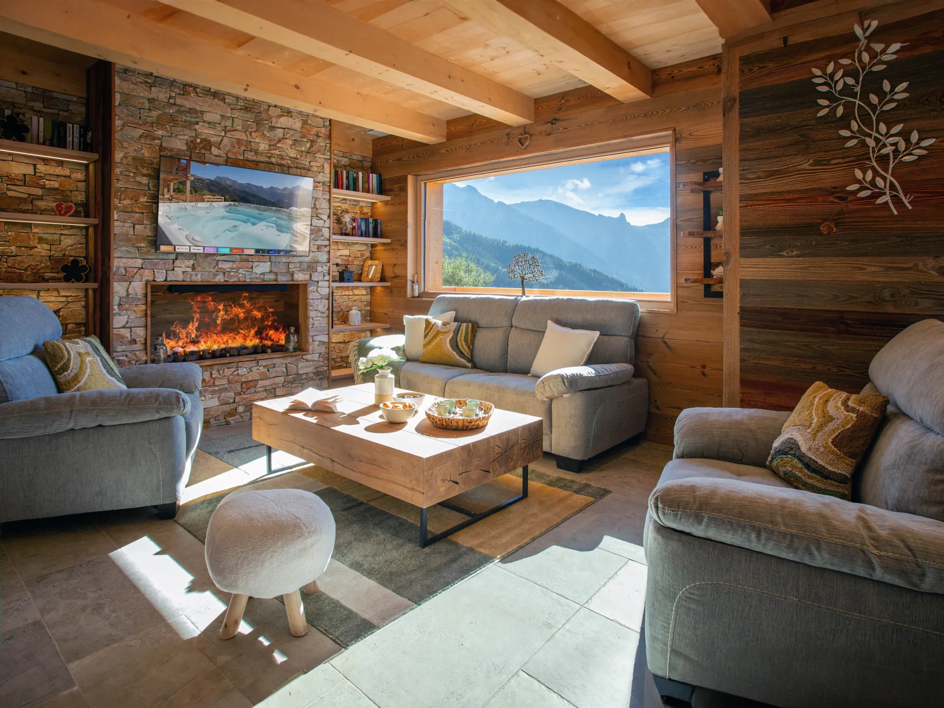 Salon intimiste avec cheminée et vue montagne. Un cocon chaleureux pour des soirées paisibles après une journée en plein air.