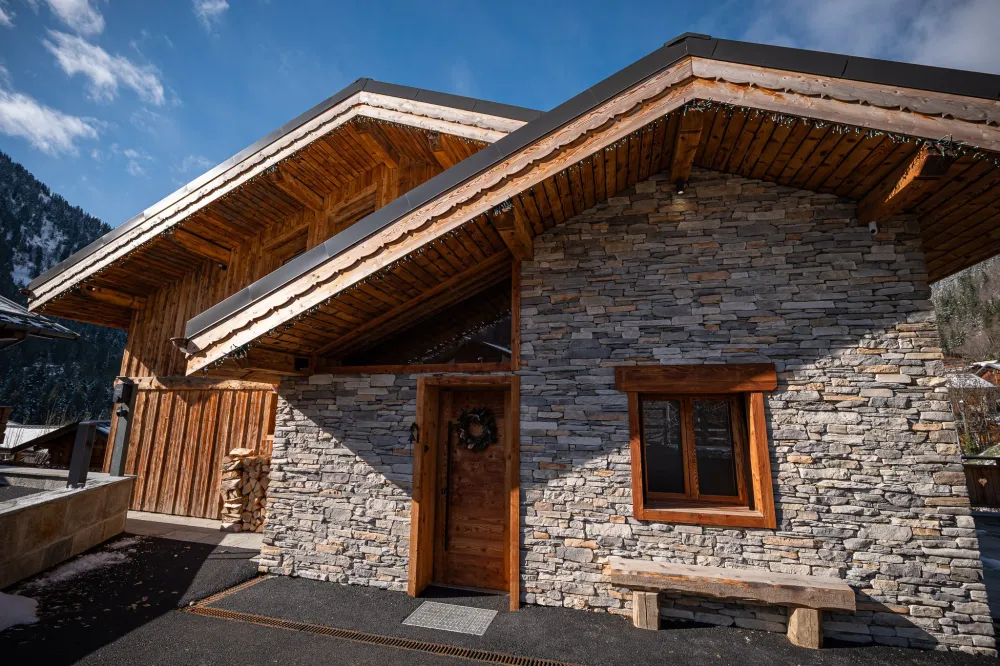 Le chalet, côté entrée, 5 places de stationnement et 2 bornes de recharge rapide pour véhicules électriques.