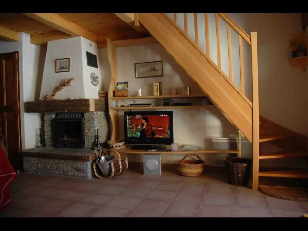 Aménagement  sous escalier montant en mezzanine, cheminée avec foyer fermé, étagère avec écran plat LCD, radio/lecteur multiple (Divx, DVD, etc)