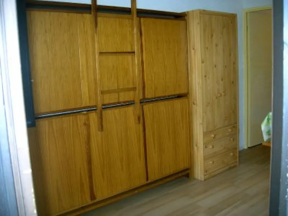 2 lits superposés repliables contre le mur + armoire de rangement dans le fond de la pièce