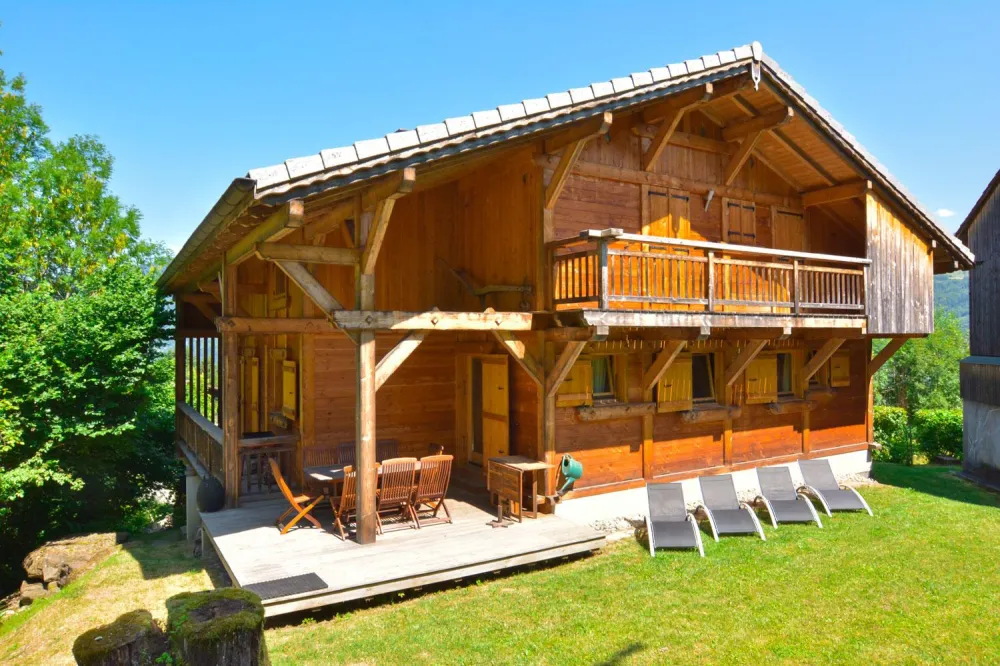 Le chalet en été côté Sud. La terrasse avec son équipement pour les repas. En bordure du ruisseau. 