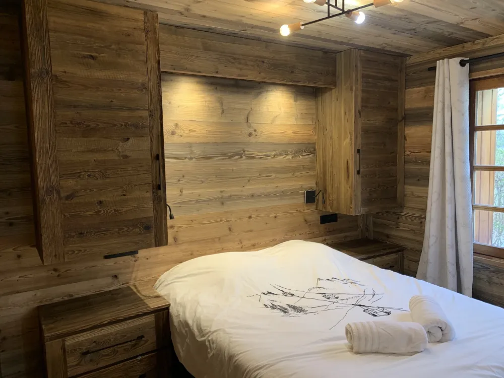 Chalet Mont-Milo : Chambre Grand Aréa rénovée en 2026. Vue vallée & montagnes, lit 160x200, literie neuve, vieux bois authentique, éclairage tamisé, rangements intégrés. Cocon idéal après vos journées en montagne