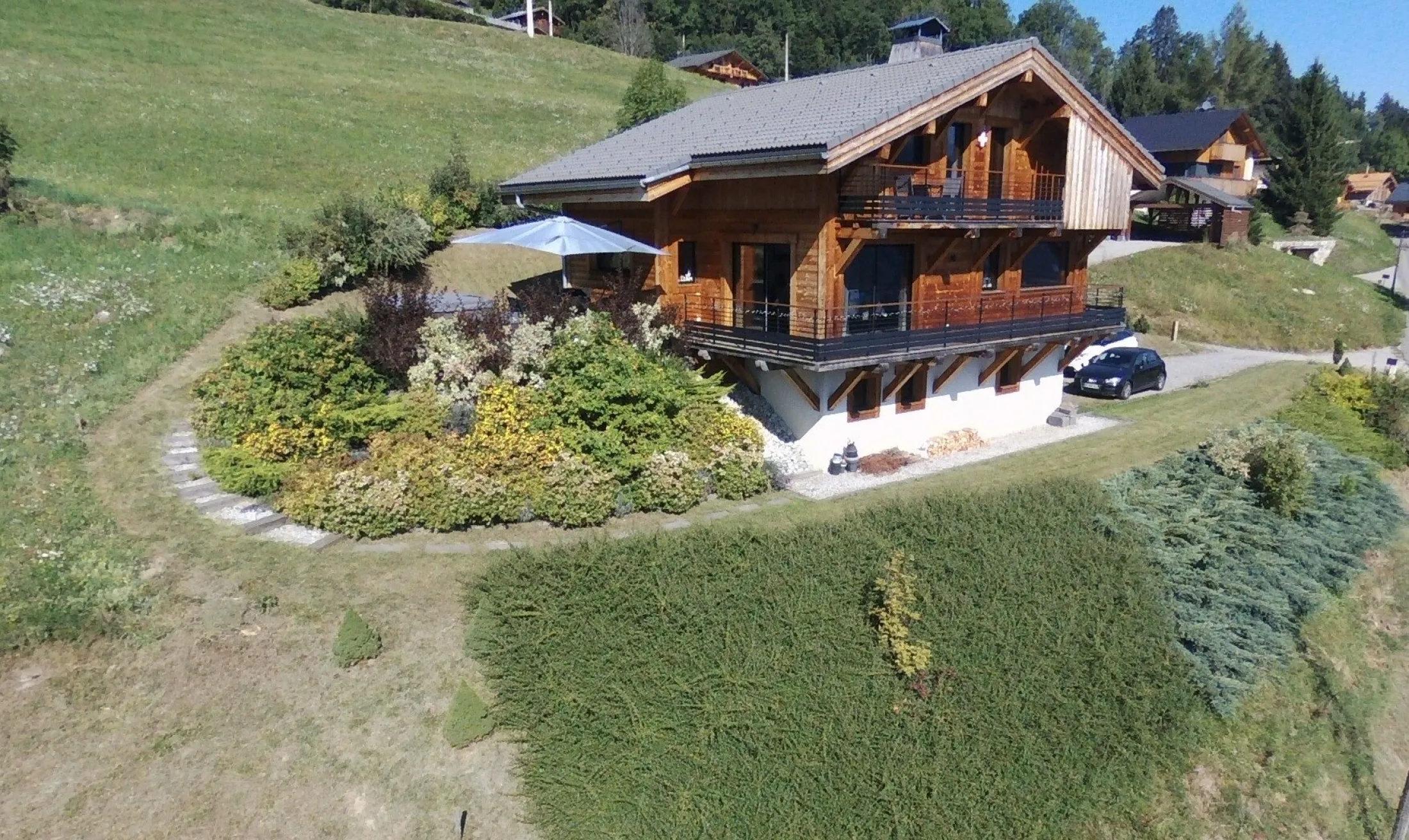 Façades Est et Sud du chalet "Le Flocon" et sa terrasse avec spa dans un environnement champêtre.