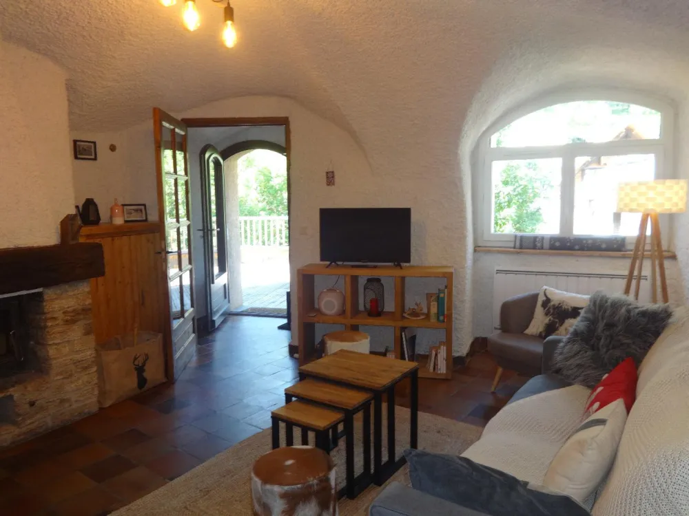Séjour avec canapé, TV et accès direct à la grande terrasse. 